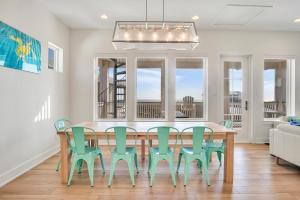 a dining room with a table and green chairs at The White House in Padre Island
