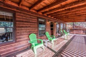 a wooden porch with green chairs and a table at The Great Escape in Ruidoso