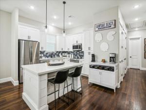 a kitchen with white cabinets and a large island with bar stools at Sandy Cheeks Surfside in Surfside Beach