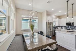 a kitchen with a dining table and a kitchen with white cabinets at Sandy Cheeks Surfside in Surfside Beach