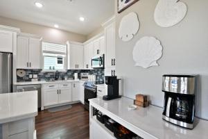 a kitchen with white cabinets and a counter top at Sandy Cheeks Surfside in Surfside Beach +33 photos