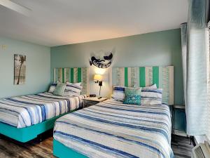 two beds in a room with blue walls at Laguna Reef #121 - Gone Coastal in Rockport