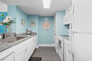 a kitchen with white cabinets and blue walls at Laguna Reef #211 - Rod and Reel in Rockport
