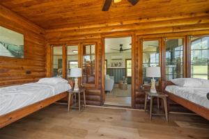two beds in a room with wooden walls and windows at Willow Heaven - Lakefront Cabin Escape in Madill