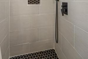 a bathroom with a shower with a black tile floor at Willow Heaven - Lakefront Cabin Escape in Madill +26 photos