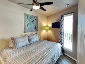 a bedroom with a bed with a ceiling fan and a window at Villa Del Sol #2138 in Corpus Christi +9 photos