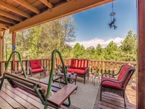 a deck with chairs and a table and a swing at Mockingbird Cabin in Ruidoso