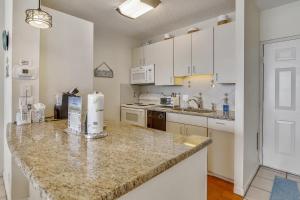 a kitchen with white cabinets and a granite counter top at Galvestonian 1002-Beachfront Getaway in Galveston +24 photos