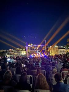 a crowd of people sitting in chairs watching a concert at Angela's house in Galaxidi