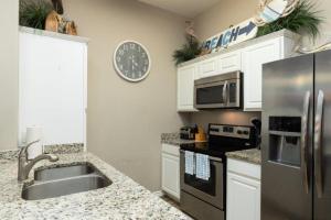 a kitchen with a sink and a stainless steel refrigerator at Lets Padre at Village by the Beach in Padre Island +20 photos