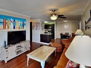 a living room with a couch and a tv and a table at Sand In Your Toes in Mustang Beach