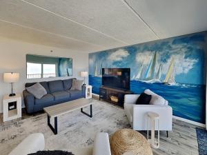a living room with a blue couch and a tv at Beachcomber 403 in Jacksonville Beach