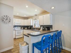 a kitchen with white cabinets and blue chairs at a counter at La Dolce Vita Playa San Luis in Galveston