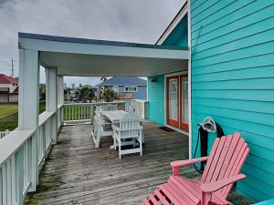 a patio with two chairs and a table on a blue house at Seagulls Landing in Galveston
