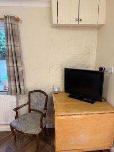 a tv sitting on top of a wooden desk with a chair at High Barn in Thursley