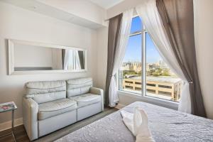 a bedroom with a bed and a couch and a window at Emerald 705 in Galveston +23 photos