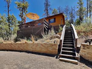 a house with a staircase leading to a house with an umbrella at Knotty Pines Cabin in Ruidoso