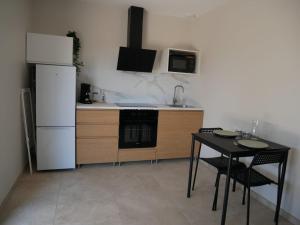 a kitchen with a table and a white refrigerator at Studios Saint Mau 3 in Saint-Maurice-de-Gourdans