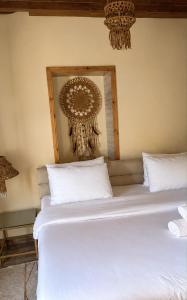 a bedroom with a white bed with a chandelier at Maison Lakala in Ben Slimane