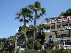 a hotel with palm trees in front of a mountain at Castillo del Mar in Almuñécar