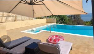 a pool with an umbrella and chairs and a table and a pool at Azure Theologos Villa in Theologos +17 photos