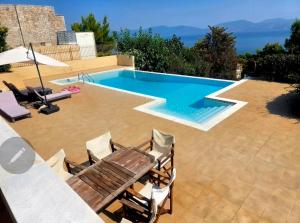 a swimming pool with a table and chairs next to it at Azure Theologos Villa in Theologos