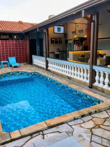 a swimming pool with blue water in front of a house at Refúgio Alemar in Ribeirão Preto