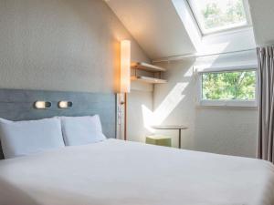 a bedroom with a white bed and a window at ibis budget Senlis in Senlis +63 photos