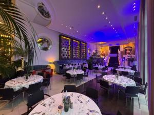a restaurant with white tables and chairs and purple ceilings at Cures Marines Hotel Thalasso & Spa Trouville - MGallery Collection in Trouville-sur-Mer