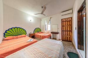 a bedroom with two beds and a ceiling fan at Hotel Naxhiely in Puerto Escondido