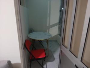 a small table and a red chair next to a door at Salão Zuzu in Ribeira Grande