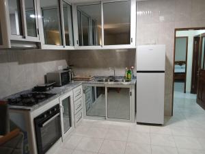 a kitchen with a white refrigerator and a sink at Salão Zuzu in Ribeira Grande