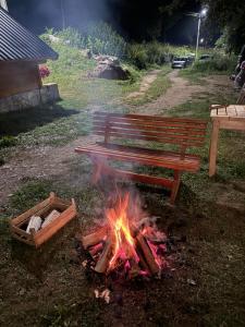 a fire next to a bench and a campfire at Bungalow-Guest House Alpina in Vusanje