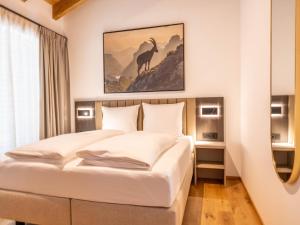 two beds in a hotel room with a painting on the wall at Dachstein Grand Alpine Lodge in Mitterberg-Schladming-Dachstein