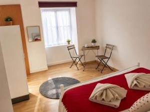 a bedroom with a red bed and a table and chairs at Casa da Prainha 4 in São Caetano