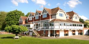 uma casa grande com um relvado em frente em Leander Club em Henley on Thames
