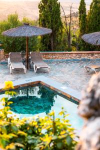 a swimming pool with two chairs and an umbrella at El Valle Dorado in El Gastor