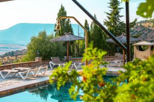 a swimming pool with chairs and umbrellas next to a mountain at El Valle Dorado in El Gastor