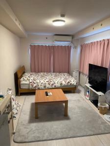 a bedroom with a bed and a table and a tv at 短期賃貸ビッグバーンズマンション田上 in Kagoshima