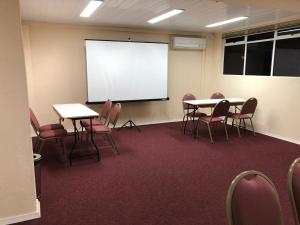 a classroom with tables and chairs and a white screen at Hotel 10 São Leopoldo in São Leopoldo