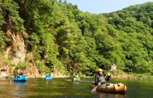 a group of people are kayaking on a river at 藤の湯えびす屋 in Yunokami