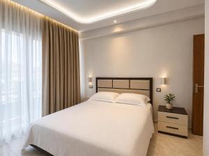 a bedroom with a white bed and a large window at ANN World in Vlorë