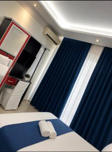 a bedroom with blue curtains and a bed with two towels at ANN World in Vlorë