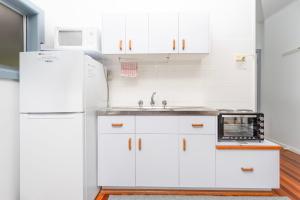 a white kitchen with a sink and a refrigerator at Koala Lodge Studio 1 in Iluka