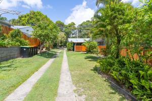 a walkway in a yard with trees and a fence at Koala Lodge Studio 1 in Iluka