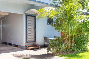 a house with a palm tree in front of it at Koala Lodge Studio 1 in Iluka +4 photos