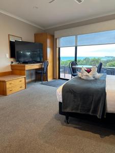 a hotel room with a bed and a flat screen tv at Baywatch Motor Lodge in Timaru