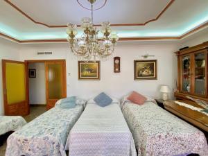 two beds in a room with a chandelier at Villa en Lorca 2 Piscinas Vistas Gran Terraza y Barbacoa-Venta Ruizo Hasta 20 personas in Lorca +56 photos