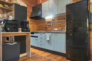 a kitchen with a large black refrigerator and wooden walls at Koguchi Village by WhyKumano in Shingū