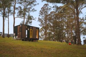 a tiny house sitting on top of a grass field at Three-Kalm & Four-Sol by Tiny Away in Rainbow Flat